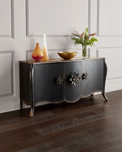 a black cabinet with two bowls on top of it and a plant in the corner