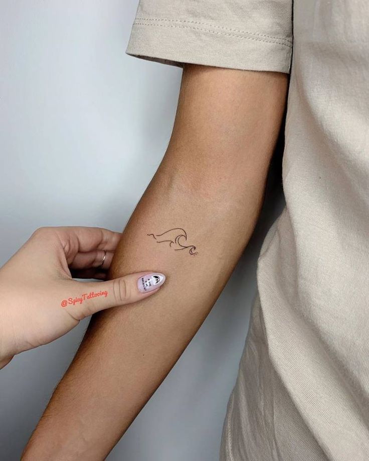 a person with a small tattoo on their arm holding onto another persons hand and pointing at it