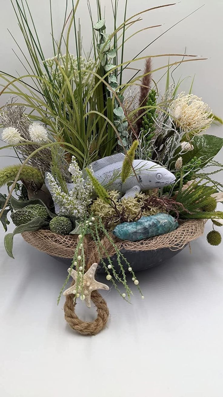 a basket filled with plants and rocks on top of a white tablecloth covered floor