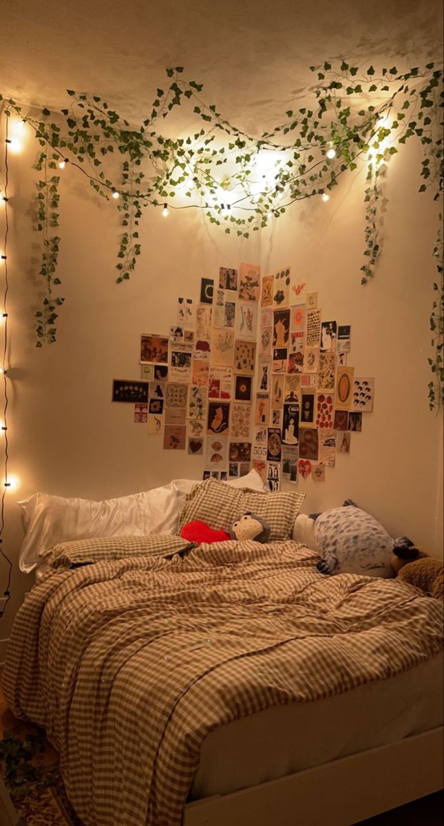 an unmade bed with lots of pictures on the wall and lights hanging above it