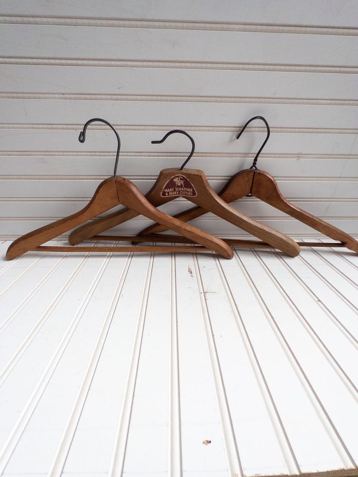 three wooden clothes hangers on a white wall