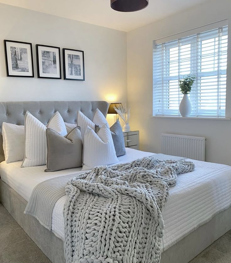 a bedroom with a bed, two lamps and pictures on the wall