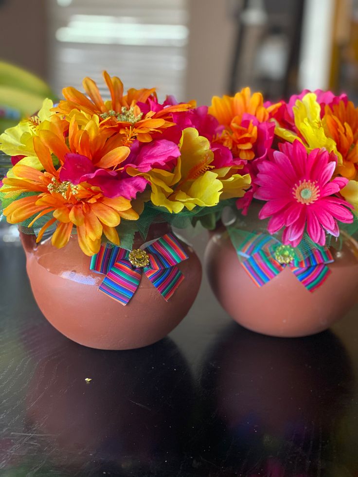 two vases filled with colorful flowers on top of a table