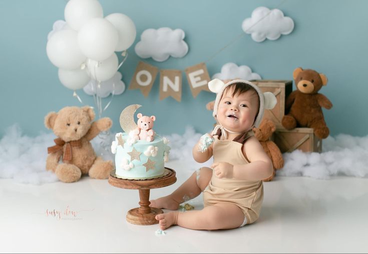 a baby sitting in front of a cake with teddy bears