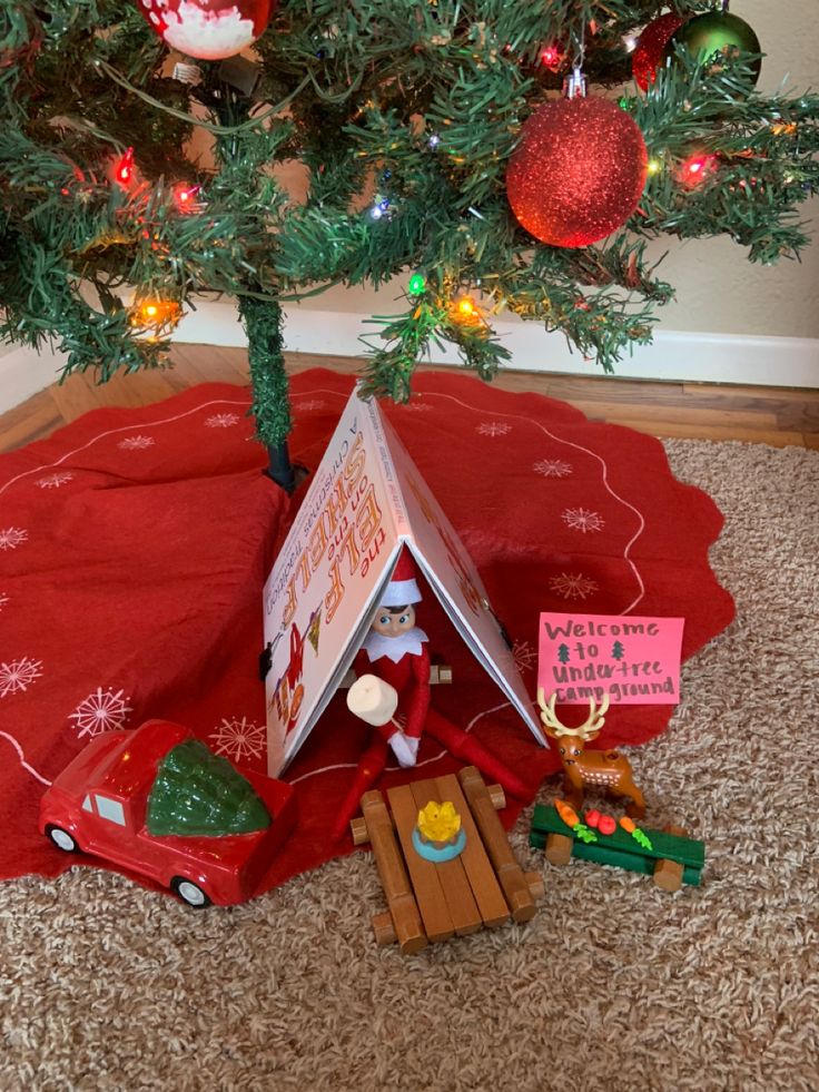 there is a small christmas tree with a house on it and a toy car underneath