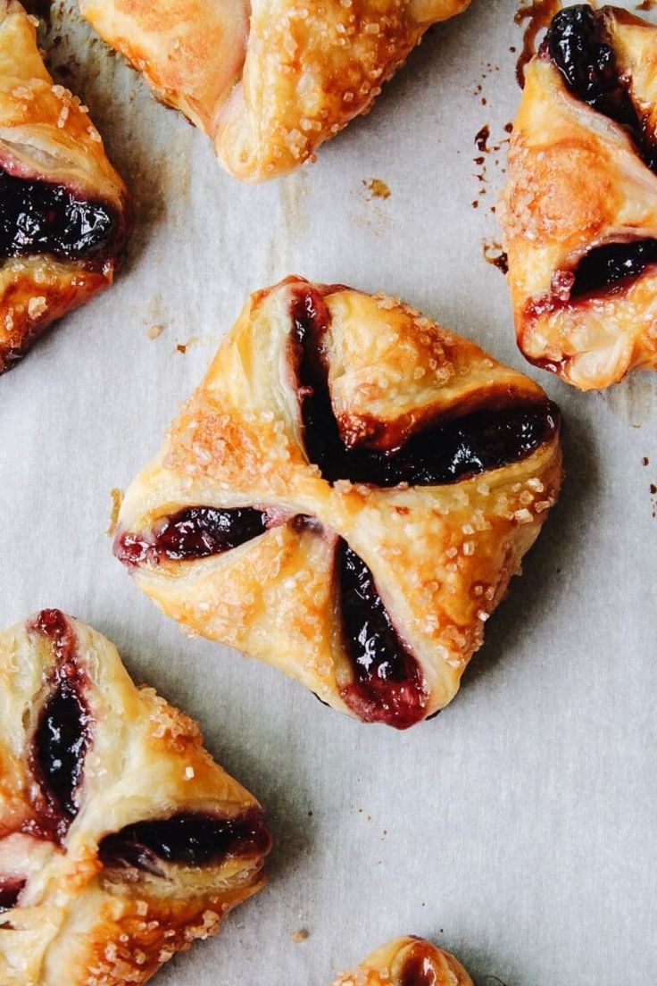 several pastries are laying on a piece of parchment paper with cranberry filling