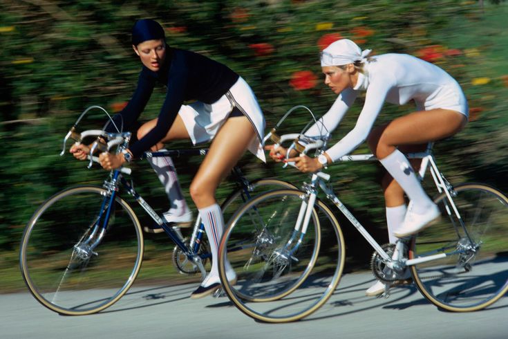 two bicyclists are riding down the street