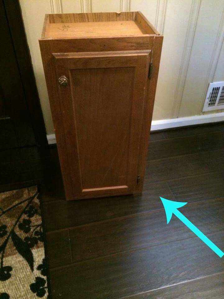 a wooden cabinet with an arrow pointing to the floor in front of it on a wood floor