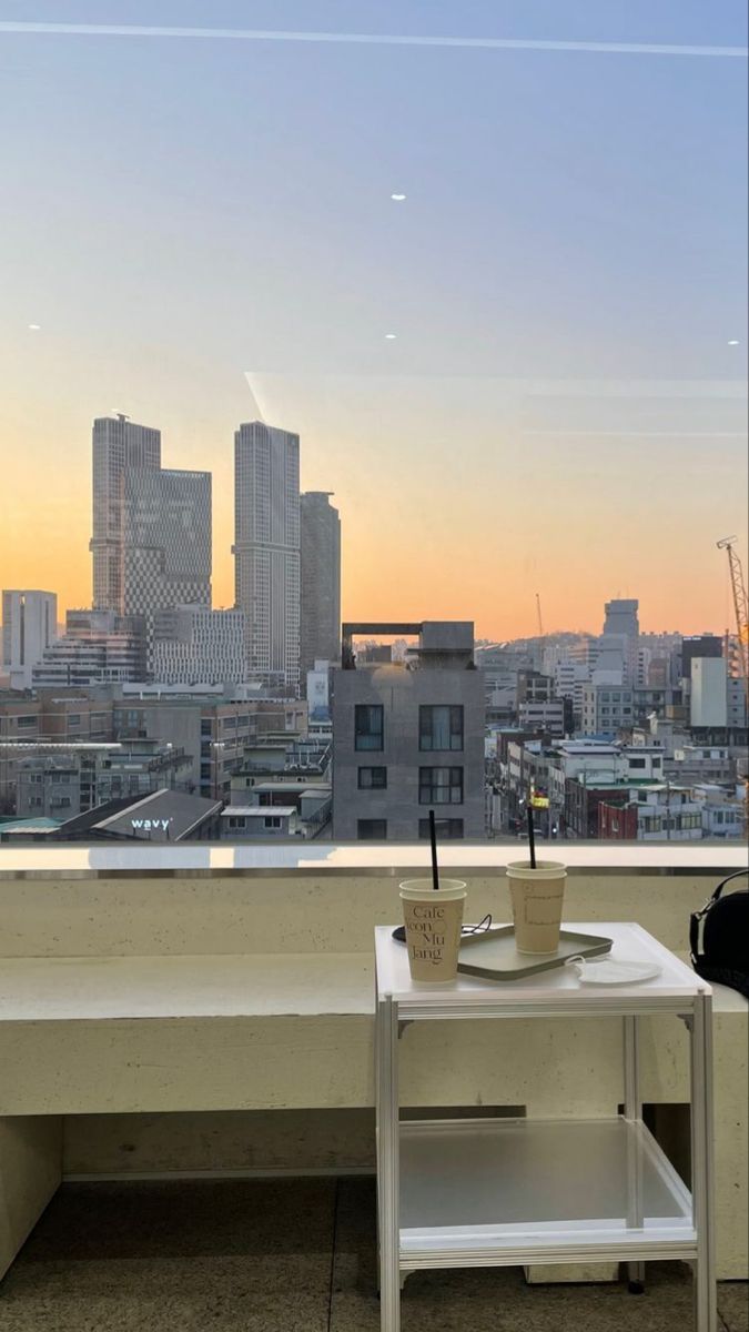 a table with a coffee cup on it in front of a window overlooking the city