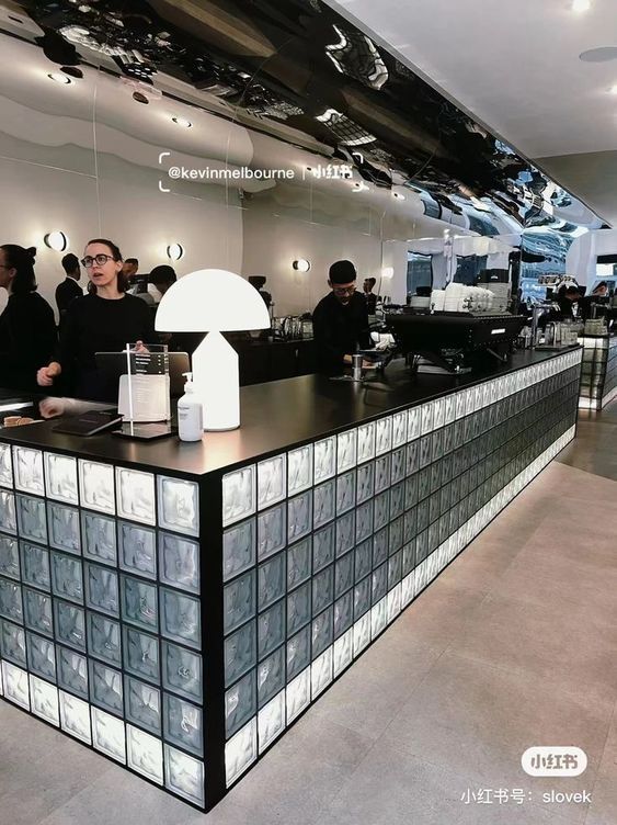 people are standing at the counter in an office lobby with black and white tiles on the walls