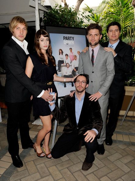 a group of people standing next to each other in front of a party sign and poster