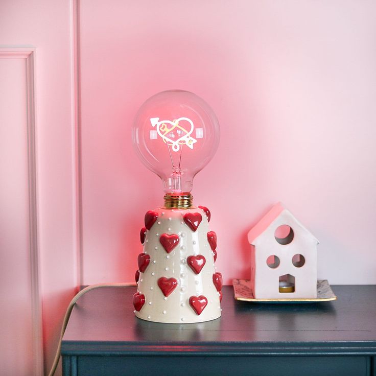 a lamp that is on top of a table next to a small house and birdhouse