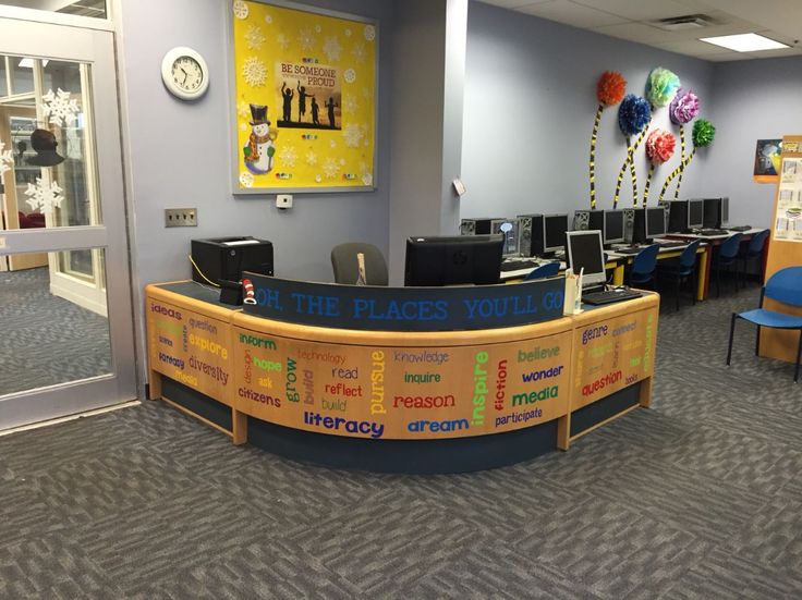 an office cubicle with desks, chairs and posters on the wall behind it