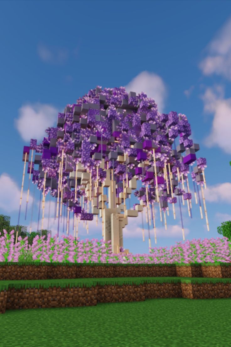 a large purple tree in the middle of a field with lots of flowers on it