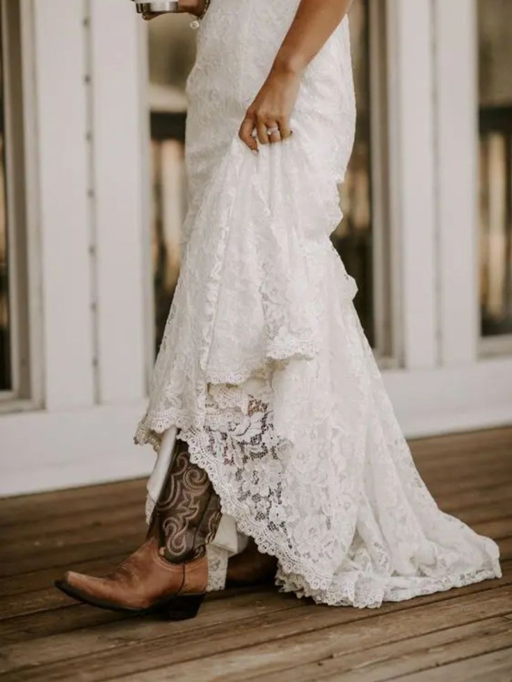 a woman in white dress and cowboy boots holding a cup