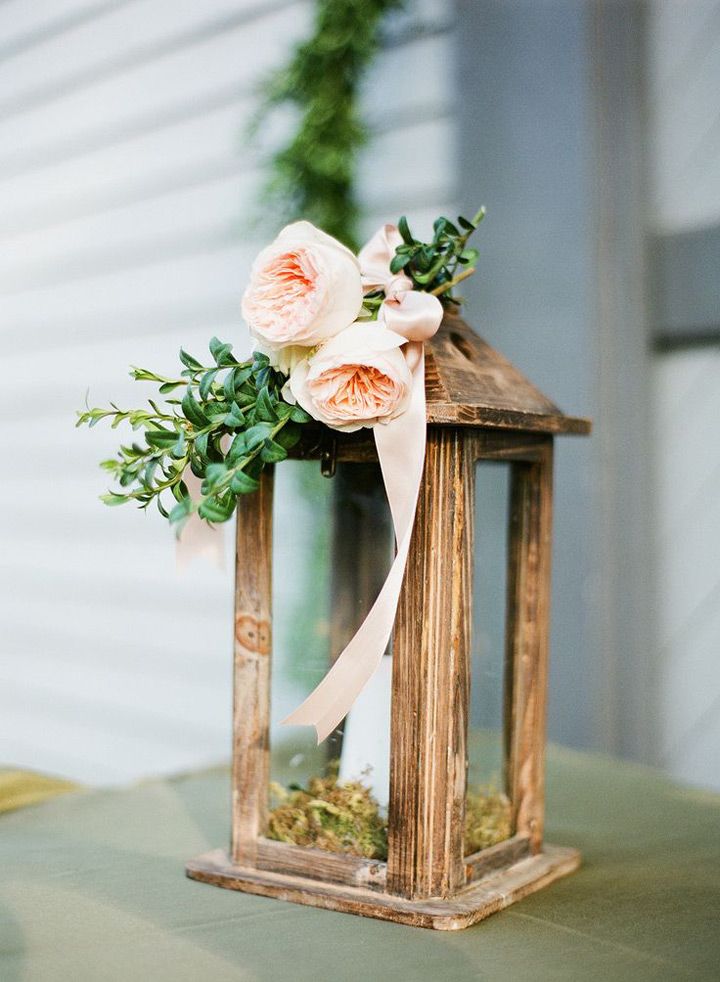 a small wooden lantern with flowers and greenery