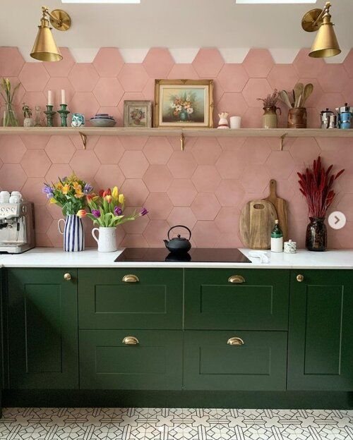 a kitchen with green cabinets and gold accents on the wall, along with potted plants