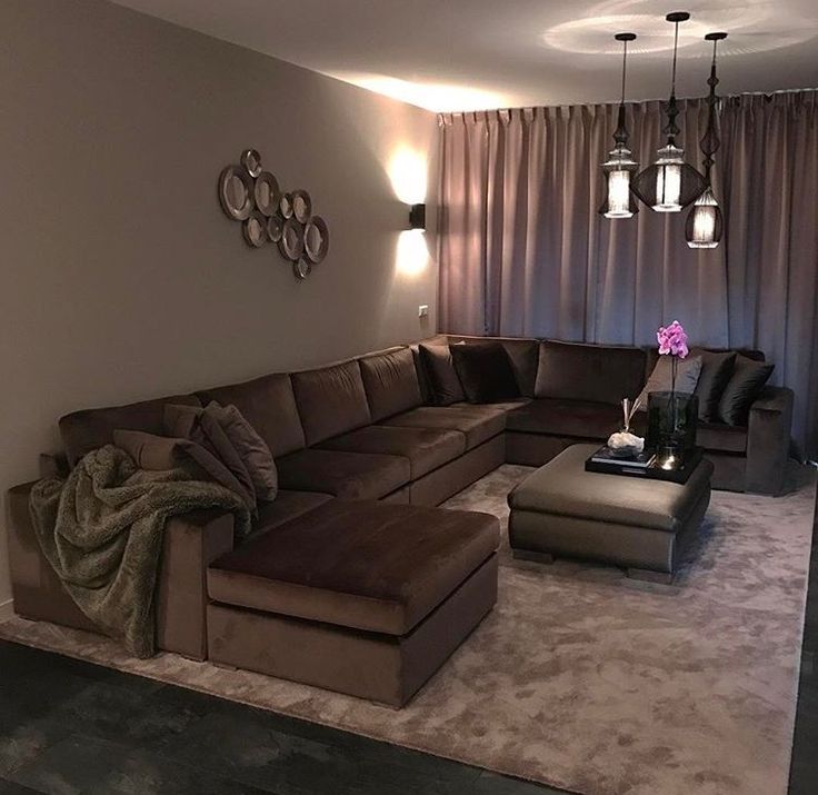 a living room filled with lots of furniture in front of a wall mounted light fixture