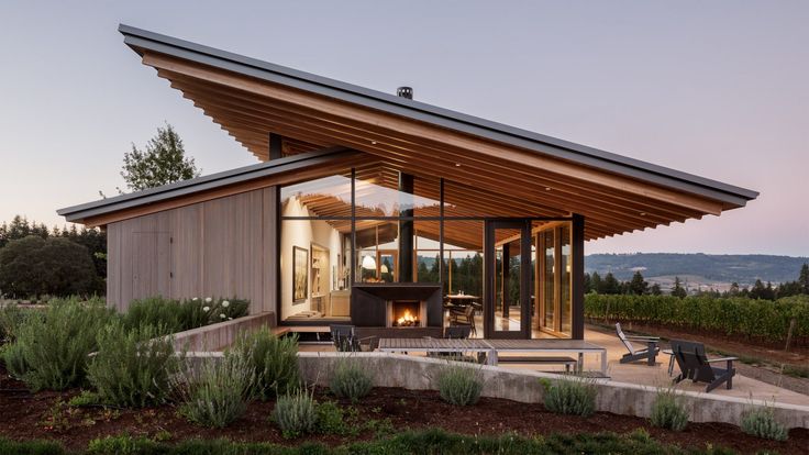 a modern house with glass walls and wooden roof