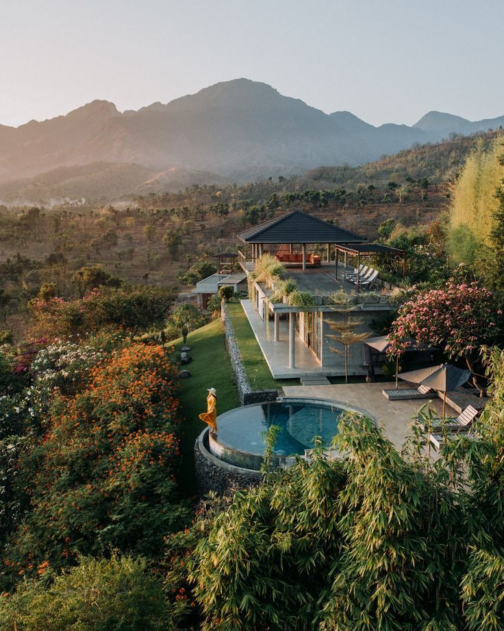 an outdoor pool surrounded by greenery and mountains