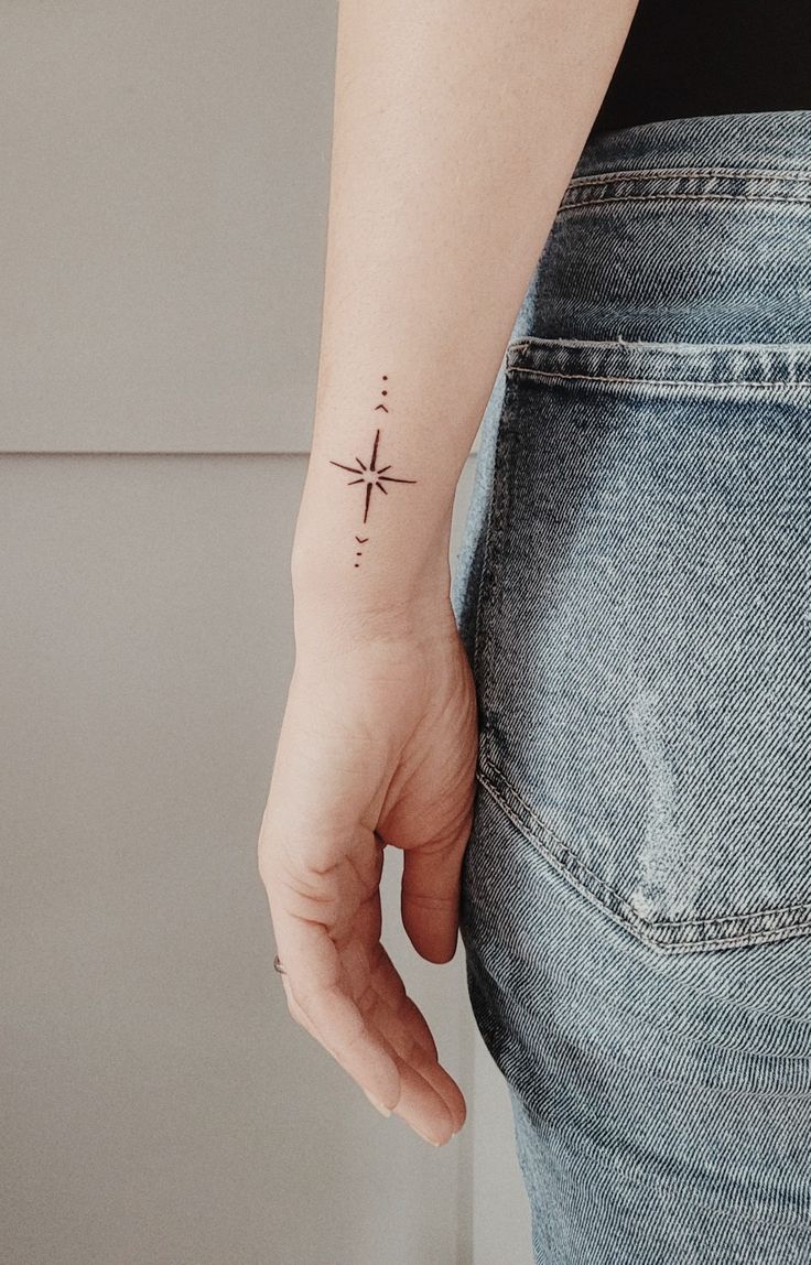 a person with a small star tattoo on their left arm and the other hand behind her back