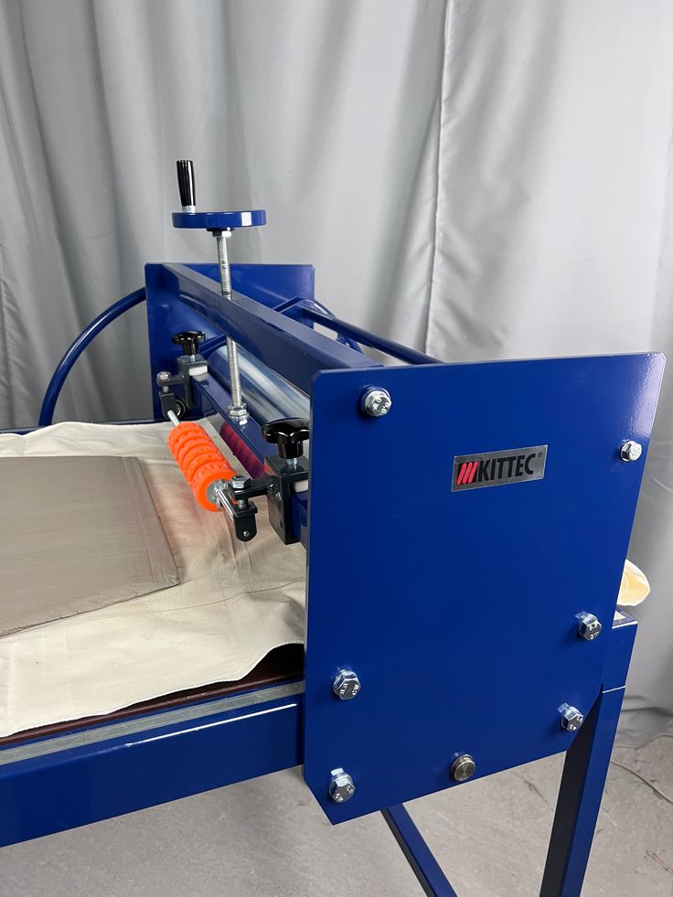 a machine that is cutting paper on a sheet with an orange object in front of it