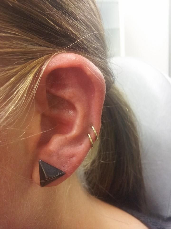 a close up of a person's ear with an earring in the shape of a triangle