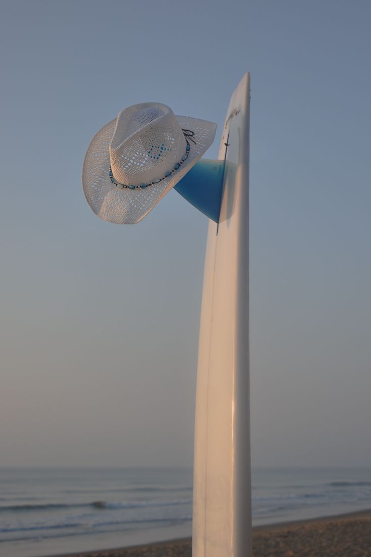 a white hat on top of a surfboard at the beach