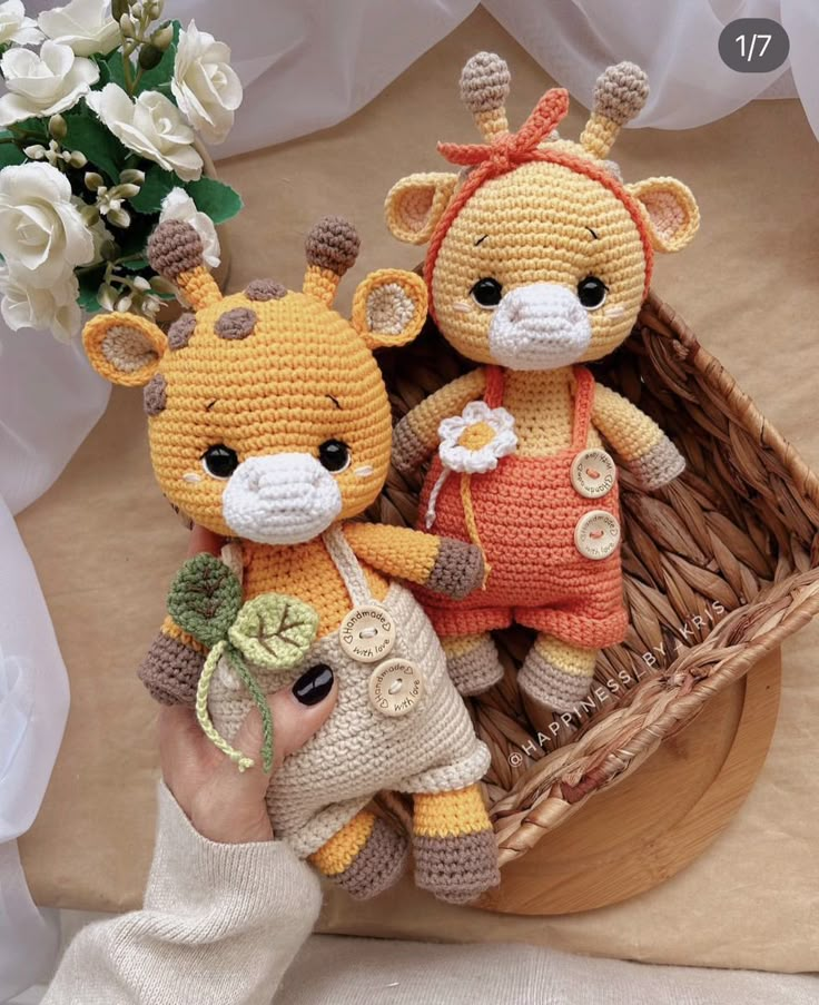 two crocheted stuffed animals sitting next to each other in a basket with flowers