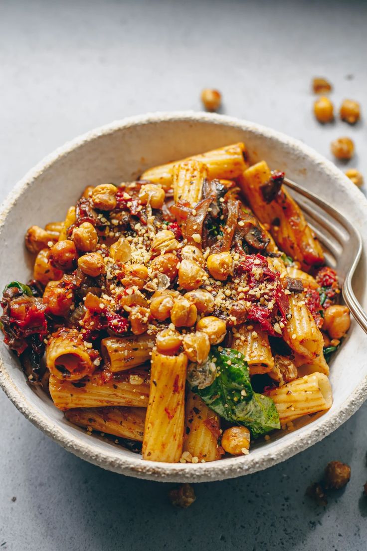 a white bowl filled with pasta and spinach