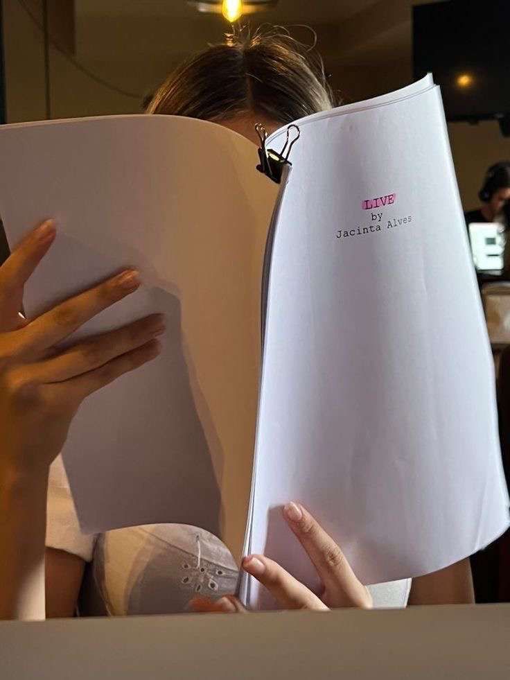 a woman is reading a book with her hands on the pages and holding it open