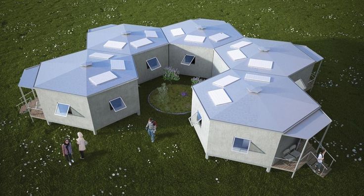 two people are standing in the grass near some small houses that have been built into each other