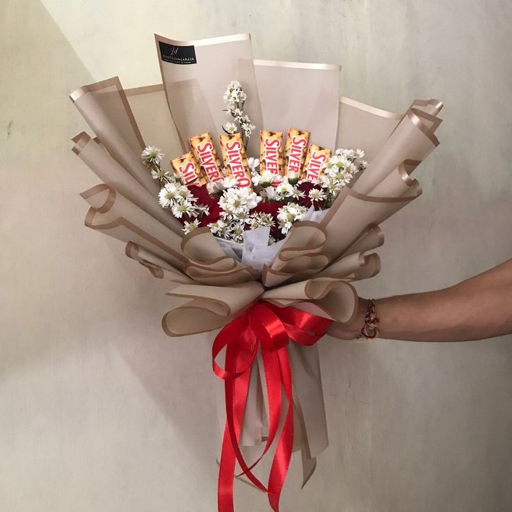 a bouquet of flowers is wrapped in brown paper and tied with a red ribbon around it