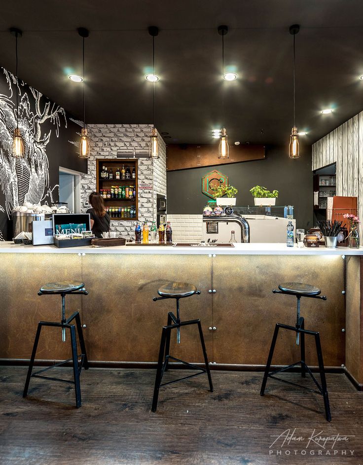 three stools sit in front of a bar with an artistic mural on the wall