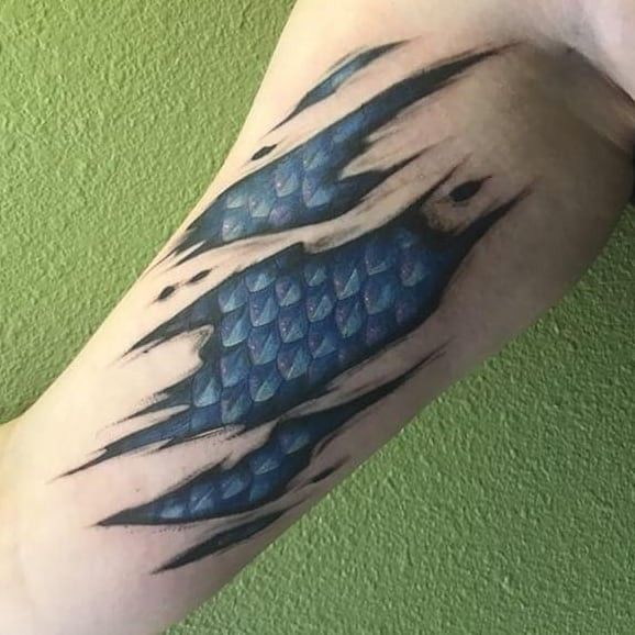 a man's arm with a blue fish tattoo on it