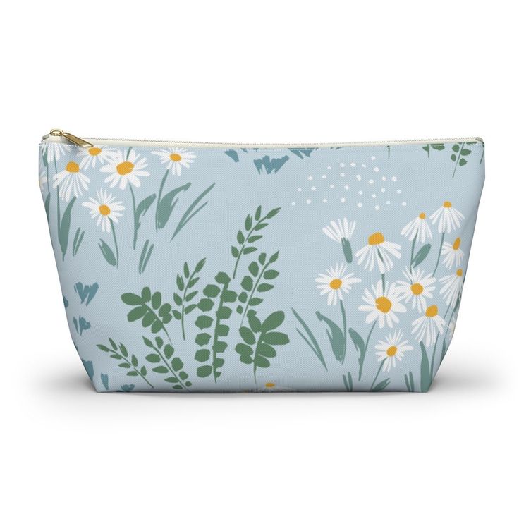 a blue and white flowered cosmetic bag with daisies on the front, butterflies in the background