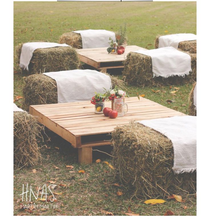 some hay bales with apples and flowers on them sitting in the middle of a field