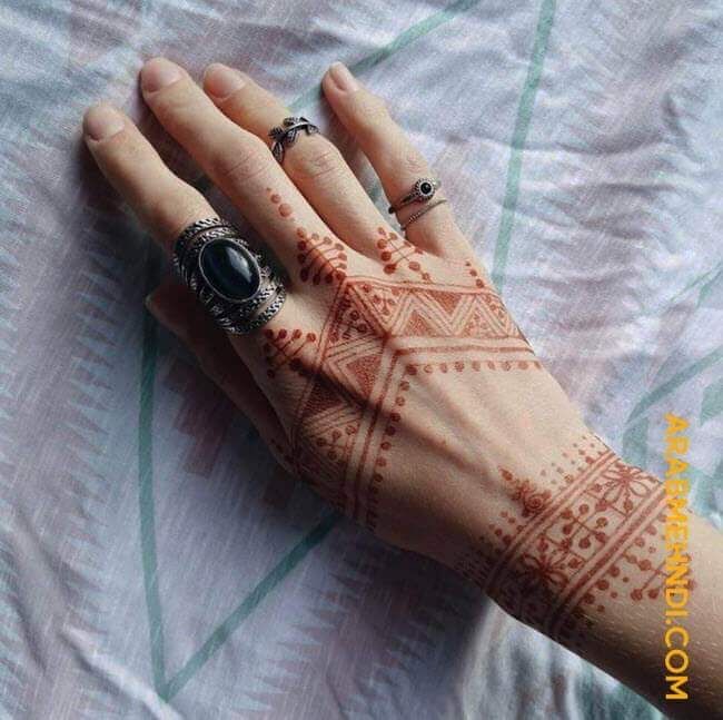 a woman's hand with henna tattoos on it and two rings in the middle