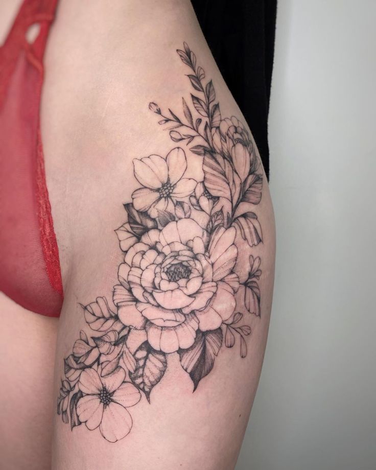 a woman's thigh with flowers and leaves tattoo on her side ribcage