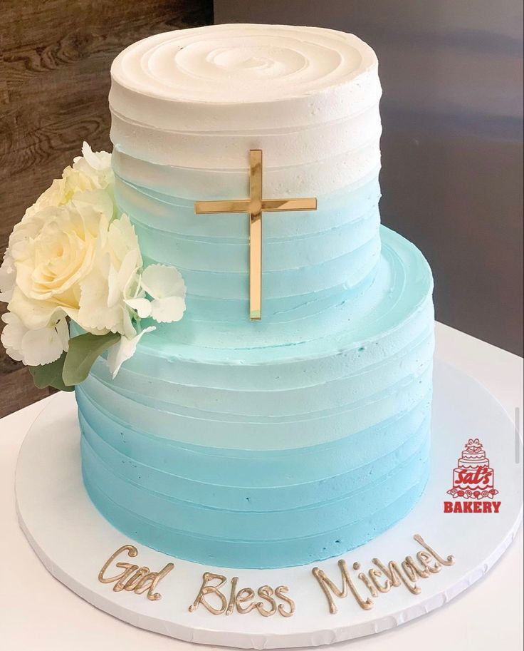 a blue and white layered cake with a cross on the top that says god's blessing