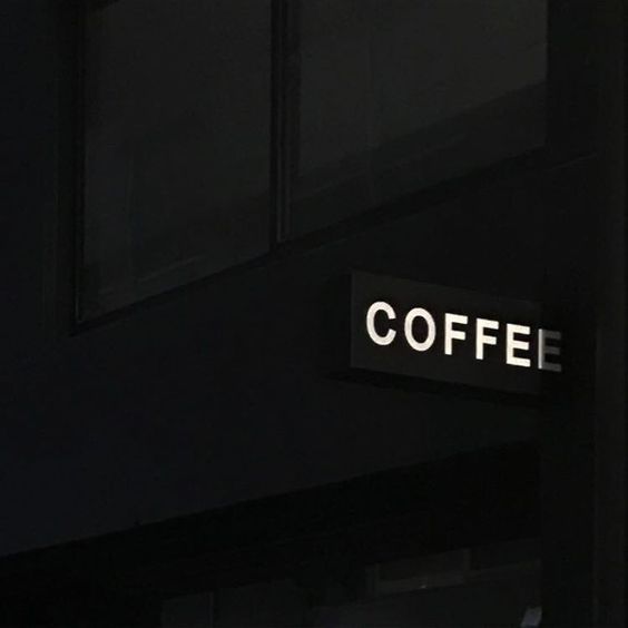 a sign that reads coffee on the side of a building in the dark night time