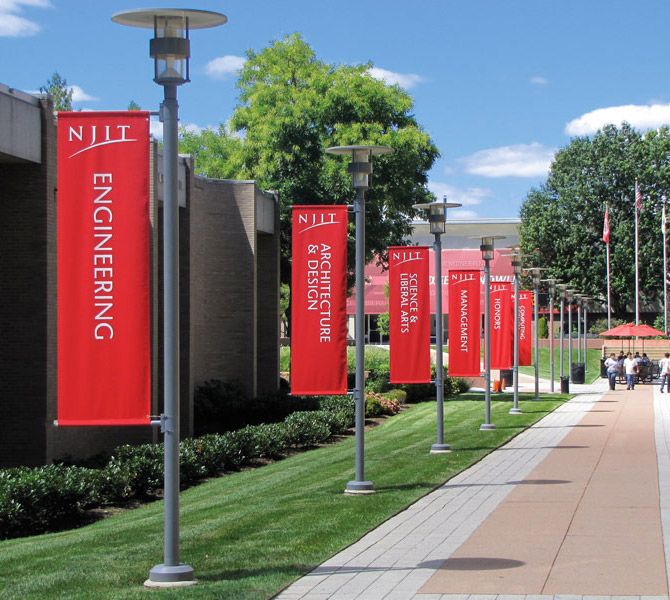 many red banners are on the side of a building with people walking down the sidewalk