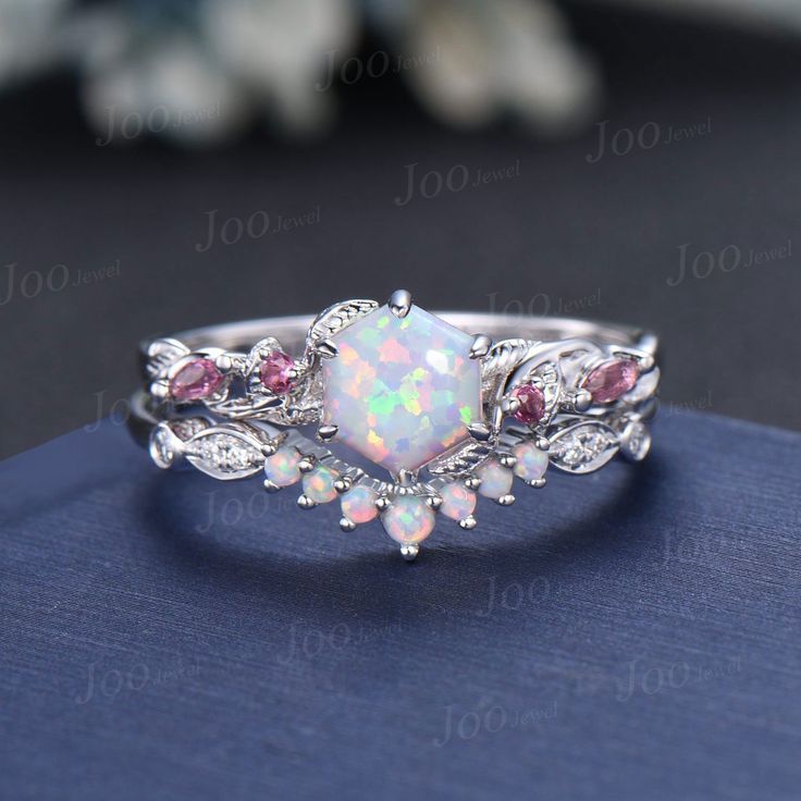 a white opal and pink tourmaline ring on top of a blue book