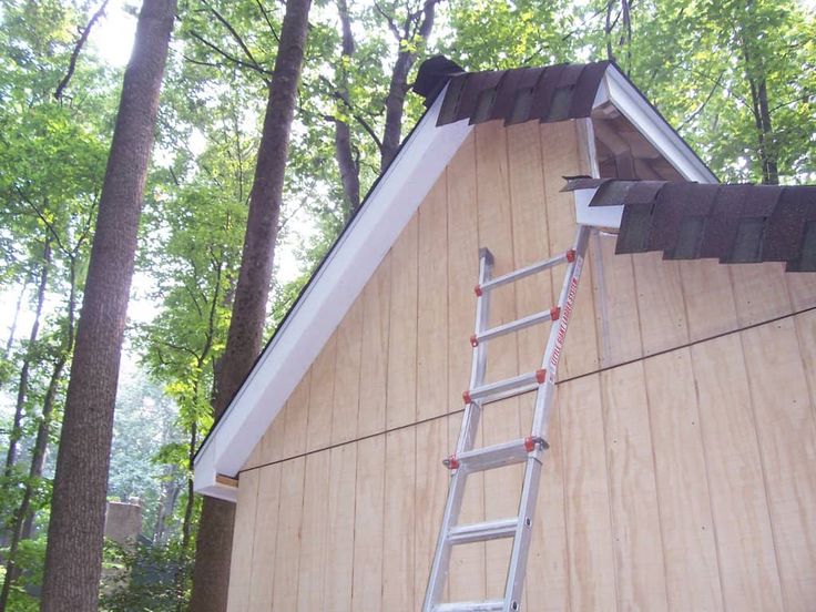 a ladder is attached to the roof of a house with wood siding and shingles