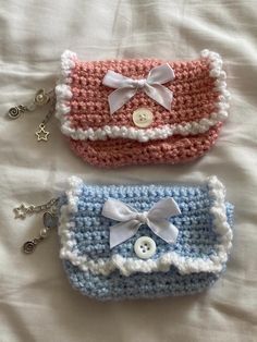 three crocheted purses are laying on a white sheet with buttons and bows