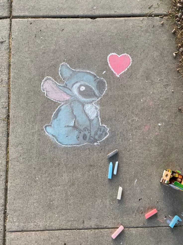 a sidewalk with some crayons on it and a drawing of a koala