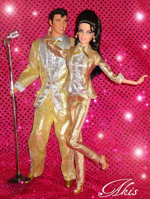 a barbie doll is posed next to a man in a gold suit with a microphone