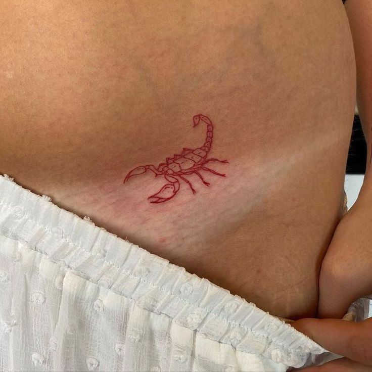 a woman's stomach with a red scorpion tattoo on it