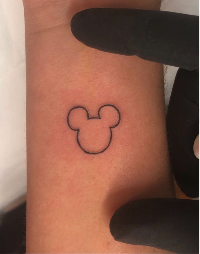 a small mickey mouse tattoo on the wrist