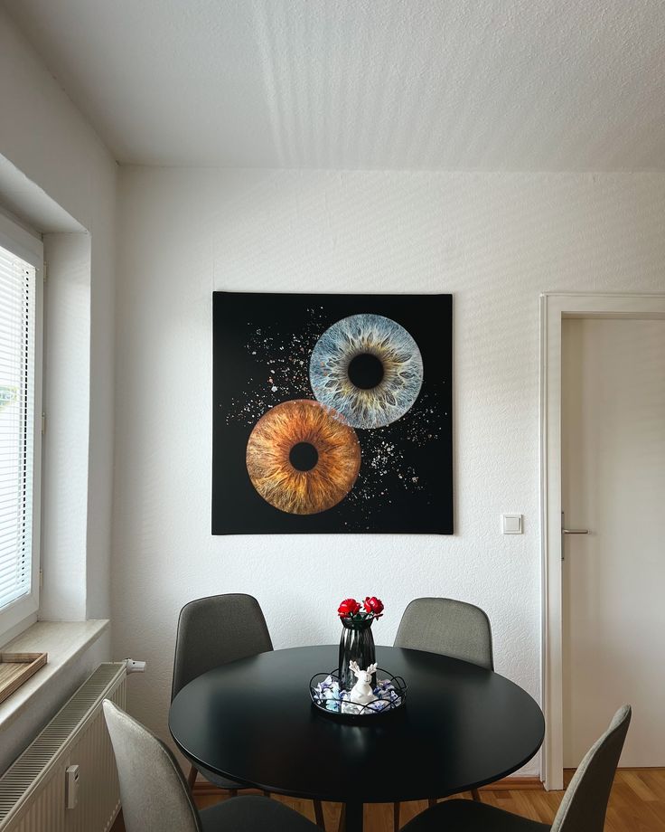 a dining room table with four chairs and a painting hanging on the wall above it